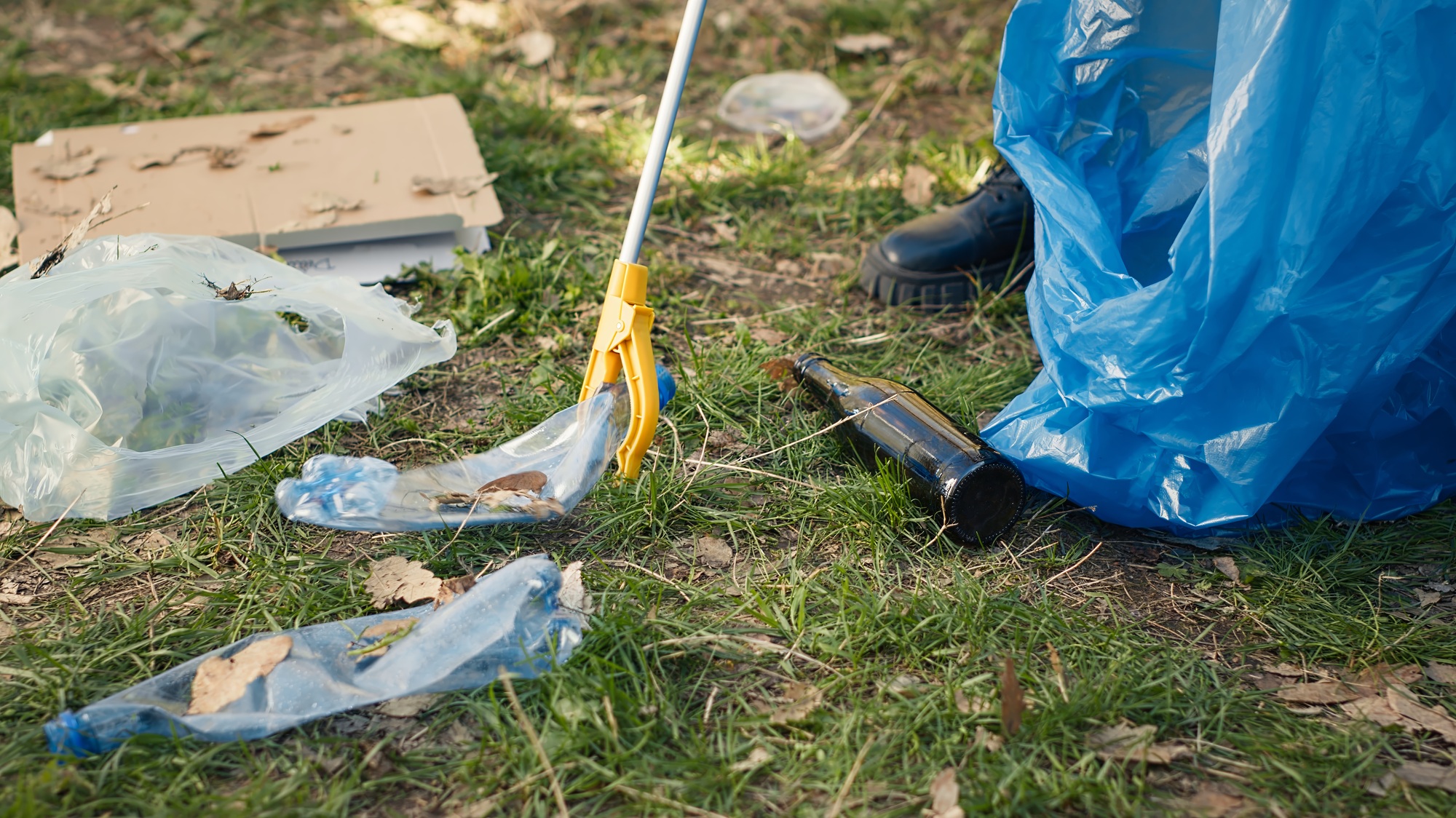 Volunteer using tongs tool to collect trash and plastic waste from the woods